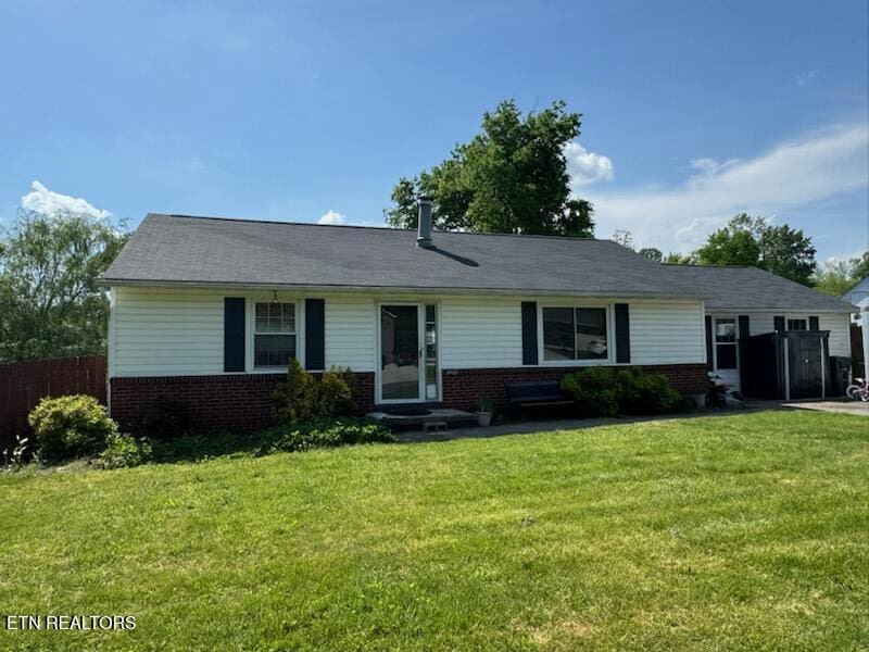 ranch-style house with fence, a front yard, and brick siding
