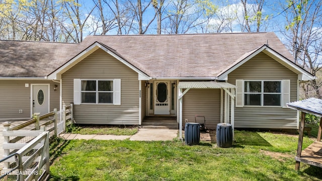 ranch-style home with a front yard, fence, and a shingled roof