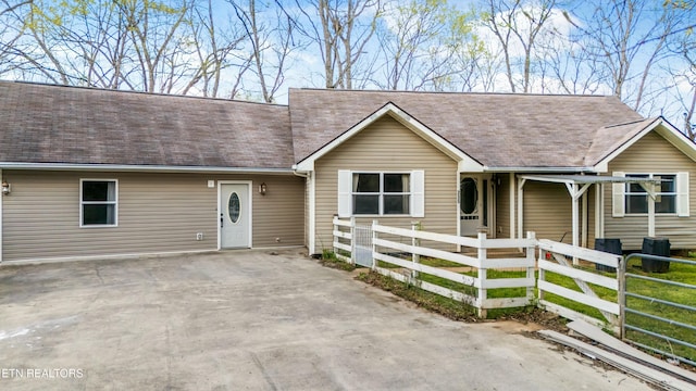 ranch-style home with a shingled roof and a fenced front yard