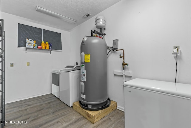 laundry room featuring electric water heater, washing machine and dryer, laundry area, and wood finished floors