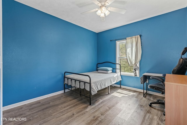 bedroom featuring baseboards, a ceiling fan, and wood finished floors
