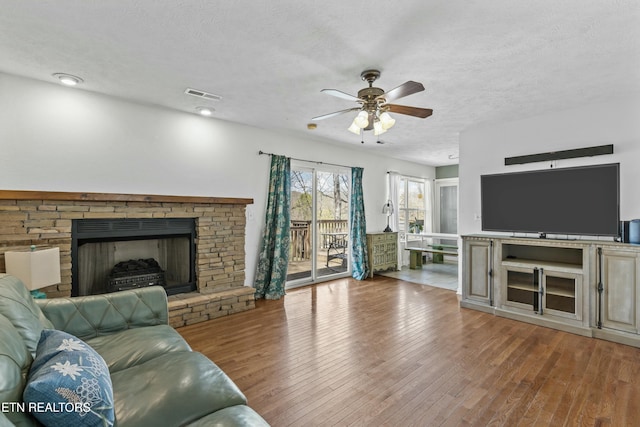 living area with hardwood / wood-style floors, visible vents, a textured ceiling, and a ceiling fan