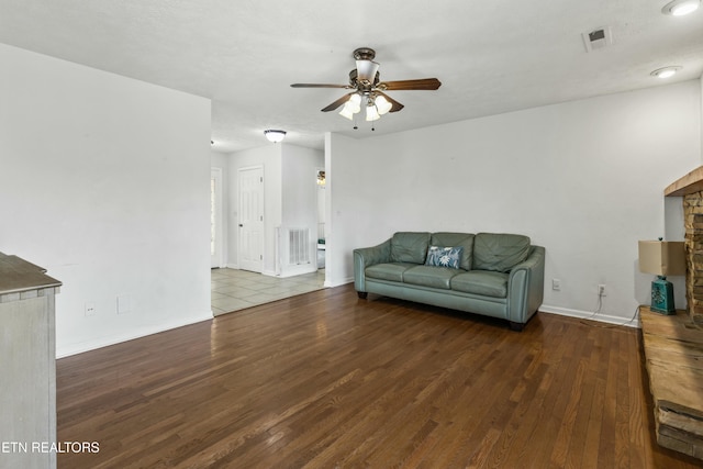 living area with visible vents, ceiling fan, wood finished floors, and a fireplace