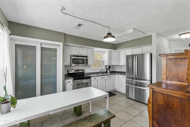 kitchen featuring dark countertops, white cabinets, visible vents, stainless steel appliances, and a sink