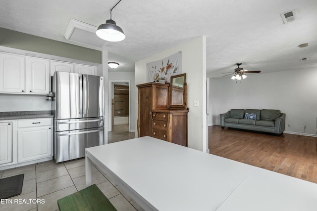 kitchen featuring visible vents, ceiling fan, freestanding refrigerator, light wood-style floors, and white cabinetry