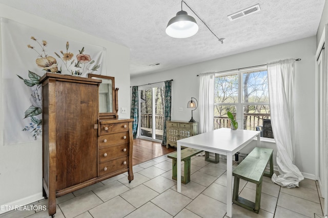 dining room with visible vents, baseboards, light tile patterned floors, and a textured ceiling