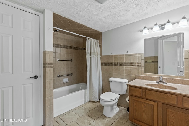 full bath with vanity, shower / bath combo, tile patterned flooring, a textured ceiling, and tile walls
