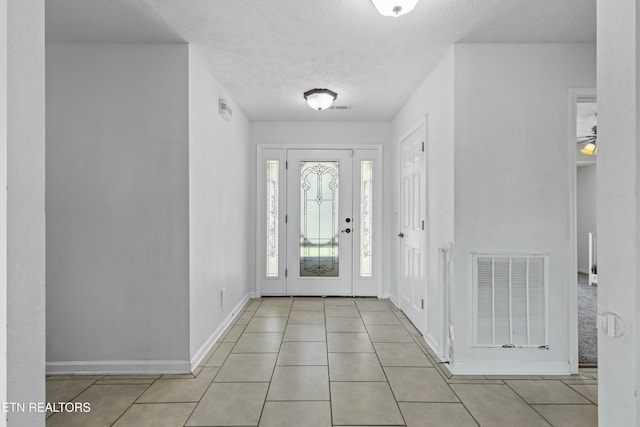 foyer with visible vents, baseboards, light tile patterned floors, and a textured ceiling