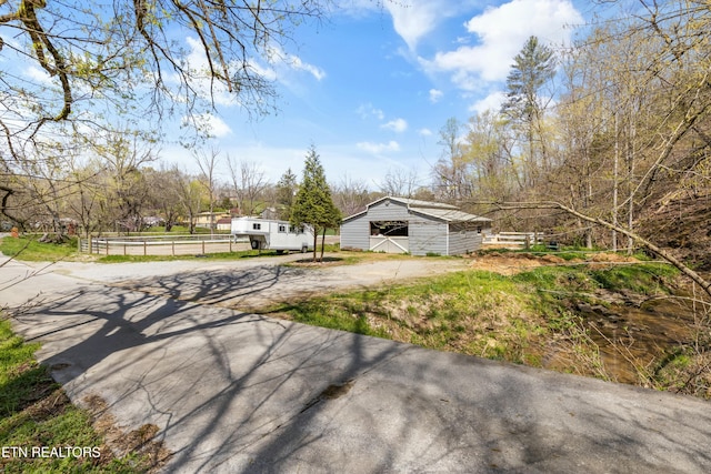 exterior space with an outbuilding, fence, and driveway