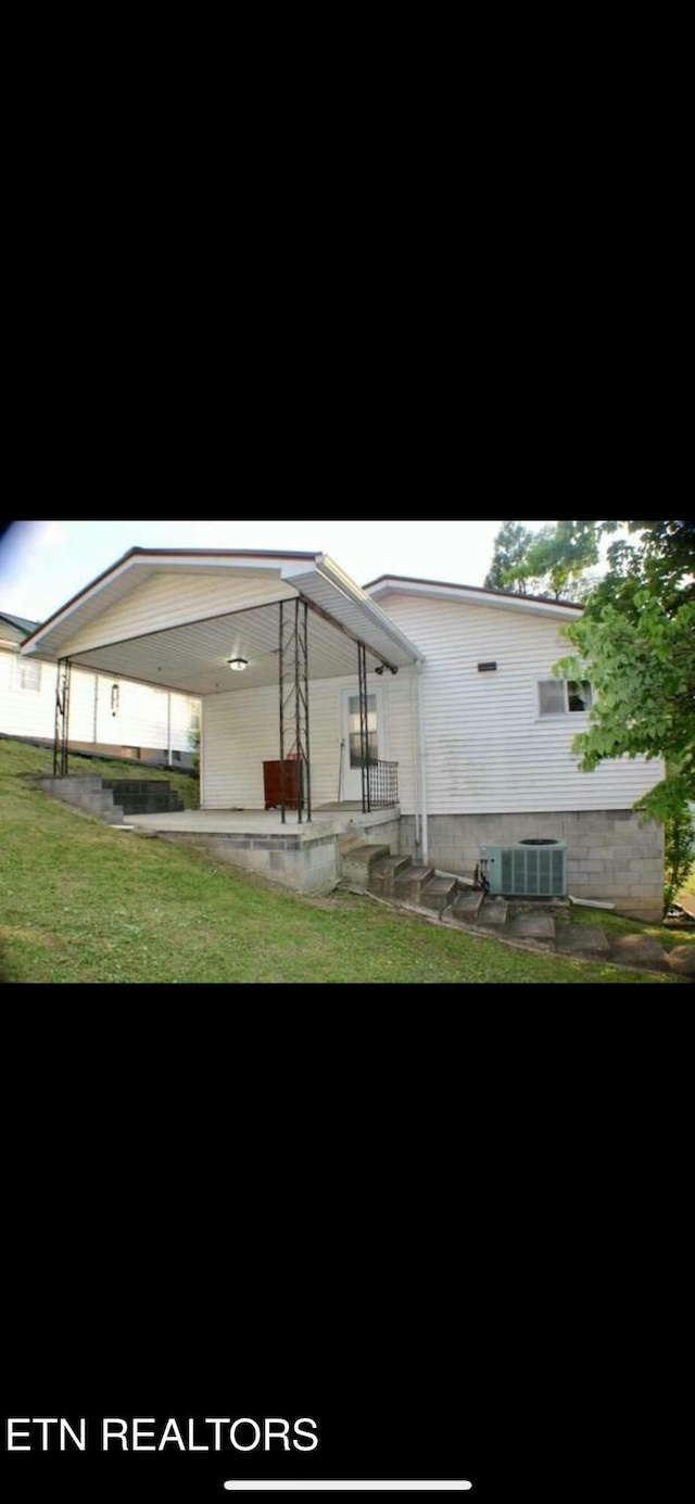 rear view of property featuring central air condition unit, a patio area, and a lawn