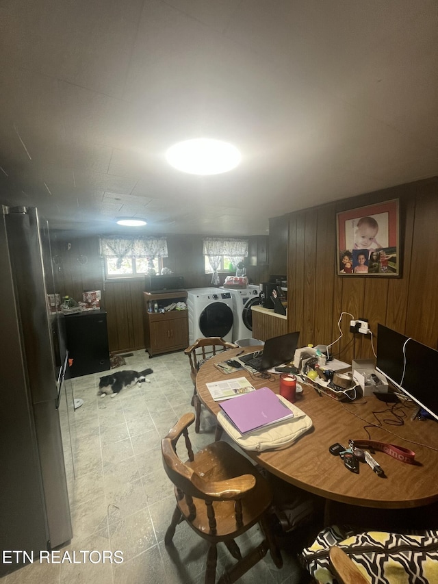 dining space with wood walls, washing machine and clothes dryer, and light floors