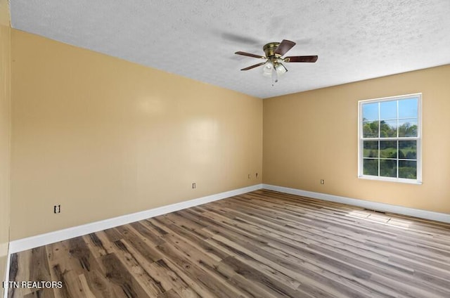 unfurnished room with baseboards, ceiling fan, a textured ceiling, and wood finished floors