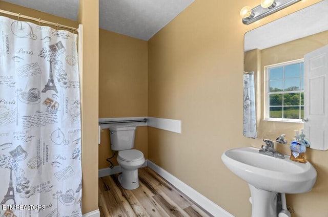 bathroom featuring a shower with shower curtain, toilet, baseboards, and wood finished floors