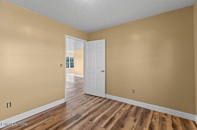 spare room featuring baseboards and wood finished floors