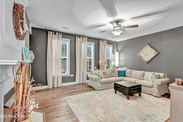 living room with wood finished floors, ceiling fan, baseboards, and visible vents