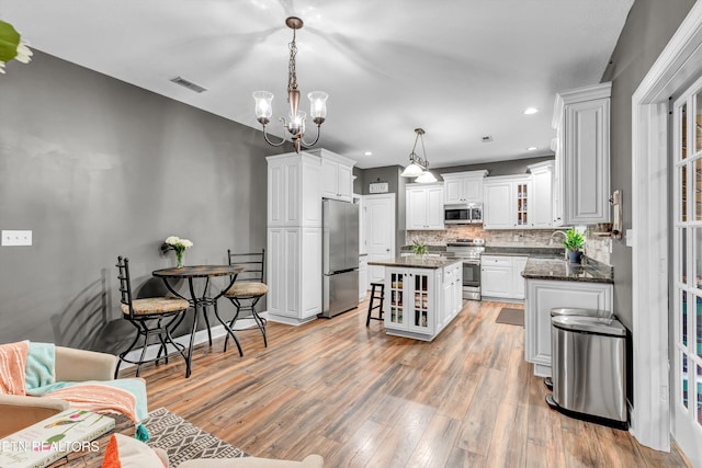 kitchen with visible vents, appliances with stainless steel finishes, light wood finished floors, backsplash, and a kitchen island