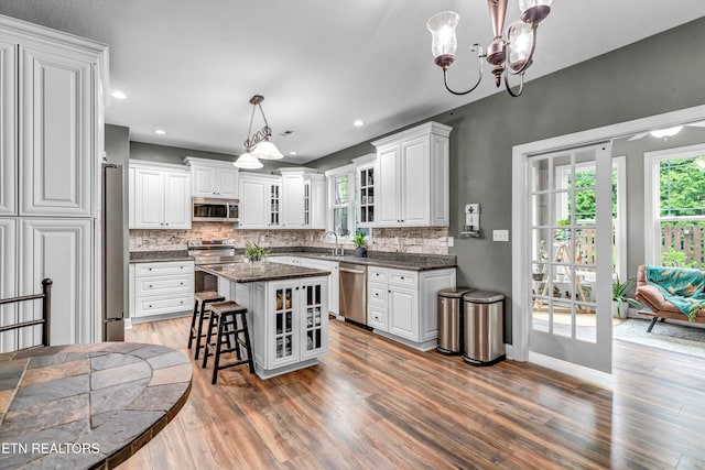 kitchen featuring white cabinets, a wealth of natural light, appliances with stainless steel finishes, a chandelier, and wood finished floors