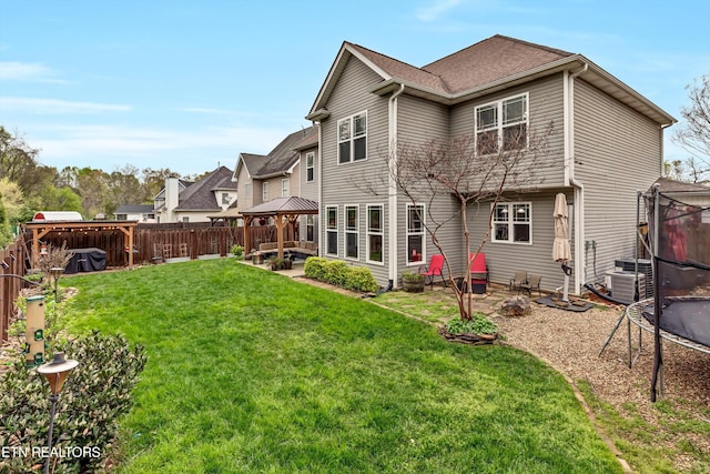 back of property with a fenced backyard, a lawn, a patio, a gazebo, and a trampoline
