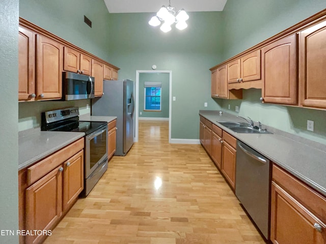 1056 Willow Creek Cir, Maryville, TN 37804 - kitchen with a notable chandelier, a high ceiling, a sink, light wood-type flooring, and appliances with stainless steel finishes