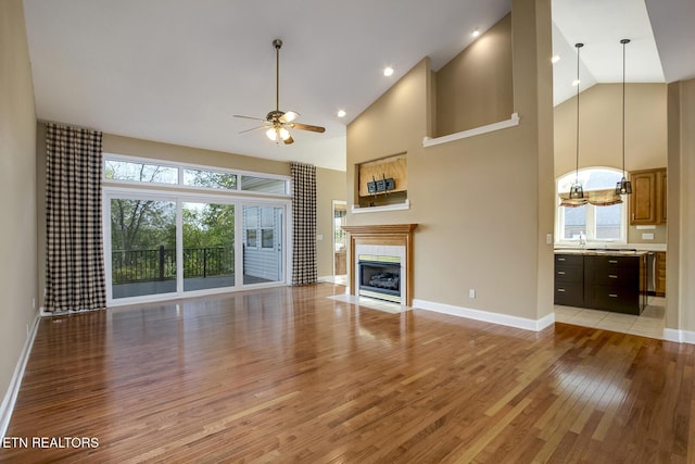 304 Coweta Ct, Loudon, TN 37774 - unfurnished living room featuring a tiled fireplace, a ceiling fan, light wood finished floors, and baseboards