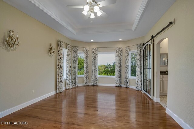 304 Coweta Ct, Loudon, TN 37774 - unfurnished room with a raised ceiling, ceiling fan, a barn door, arched walkways, and wood finished floors