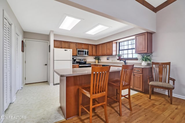 13 Oxford Cir, Fairfield Glade, TN 38558 - kitchen featuring a kitchen breakfast bar, baseboards, a kitchen island, brown cabinets, and appliances with stainless steel finishes