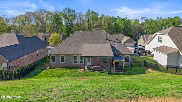 rear view of property featuring a yard, brick siding, and a fenced backyard