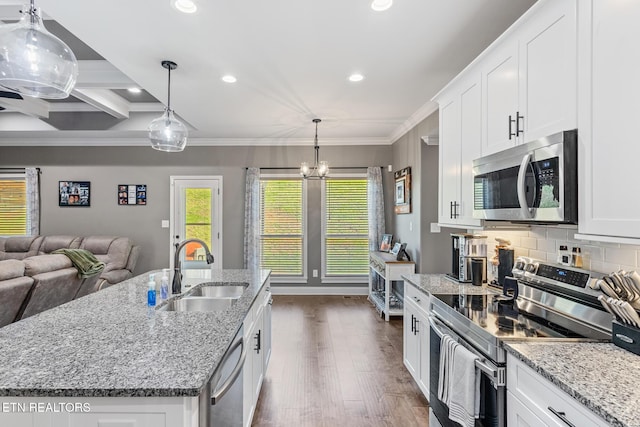kitchen featuring white cabinetry, backsplash, crown molding, stainless steel appliances, and a sink