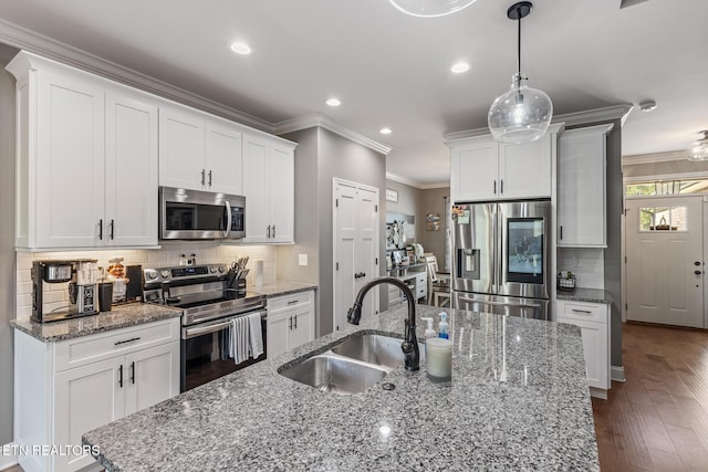 kitchen featuring white cabinets, a sink, ornamental molding, and appliances with stainless steel finishes
