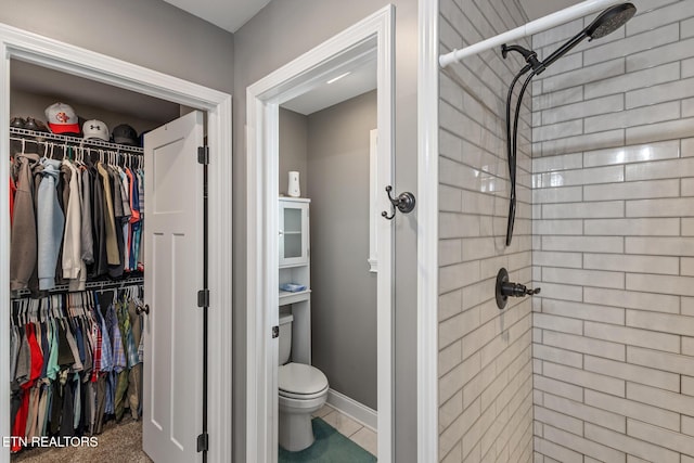 bathroom featuring toilet, a walk in closet, and a stall shower
