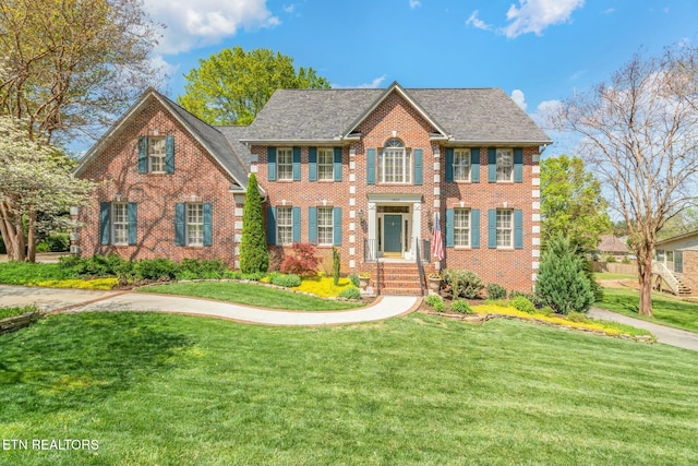 georgian-style home with a front yard and brick siding
