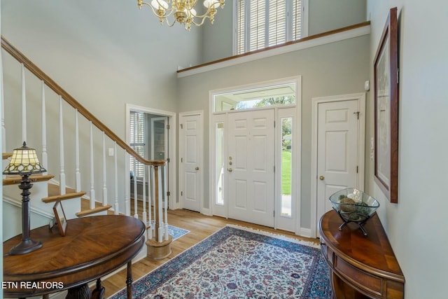 entrance foyer with light wood finished floors, a notable chandelier, stairway, and a wealth of natural light
