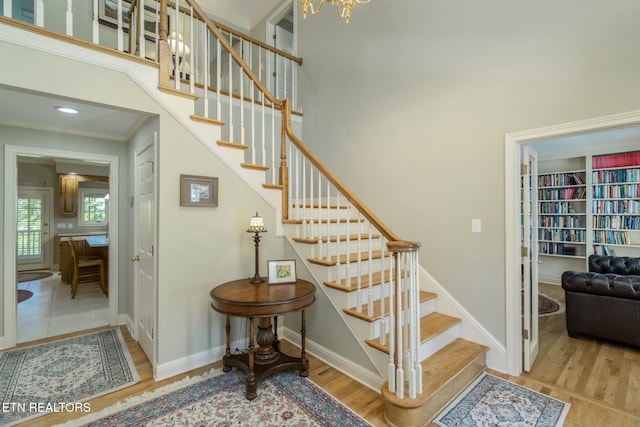 stairs featuring baseboards, a towering ceiling, and wood finished floors