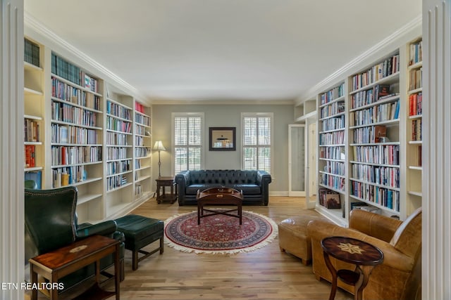 living area featuring wall of books and wood finished floors