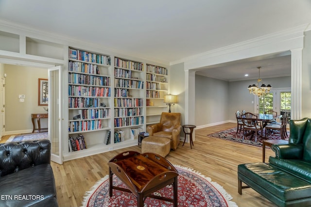 sitting room with a notable chandelier, baseboards, crown molding, and wood finished floors
