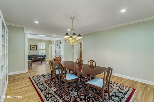 dining space with a chandelier, light wood-style floors, baseboards, and ornamental molding