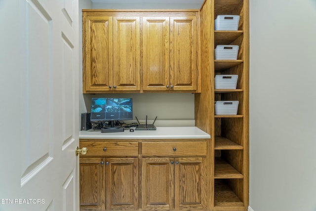 kitchen with light countertops, brown cabinetry, and open shelves