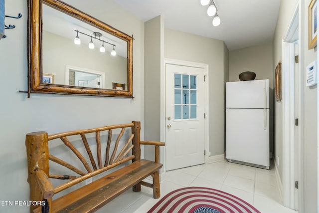 doorway to outside with baseboards and tile patterned flooring
