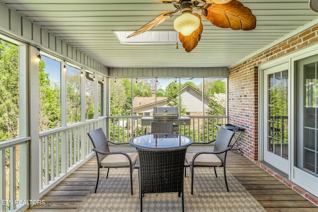 sunroom featuring a wealth of natural light, a ceiling fan, and a skylight