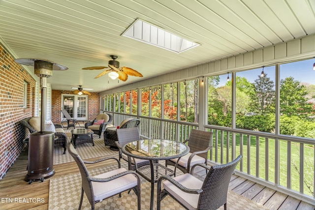 sunroom / solarium with ceiling fan, an outdoor living space, and a skylight