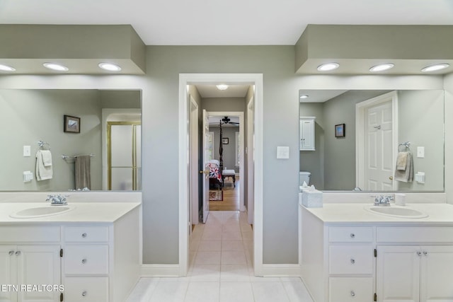 ensuite bathroom featuring a sink, two vanities, and tile patterned flooring