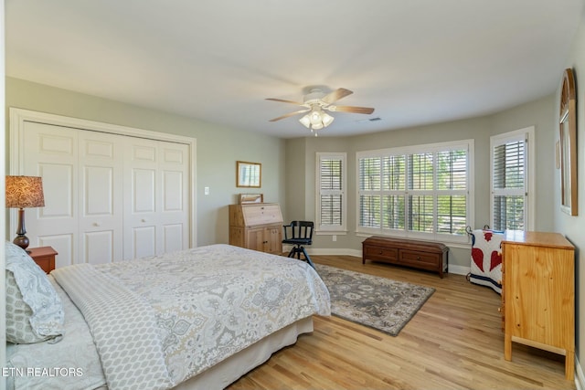 bedroom with light wood-style floors, ceiling fan, a closet, visible vents, and baseboards