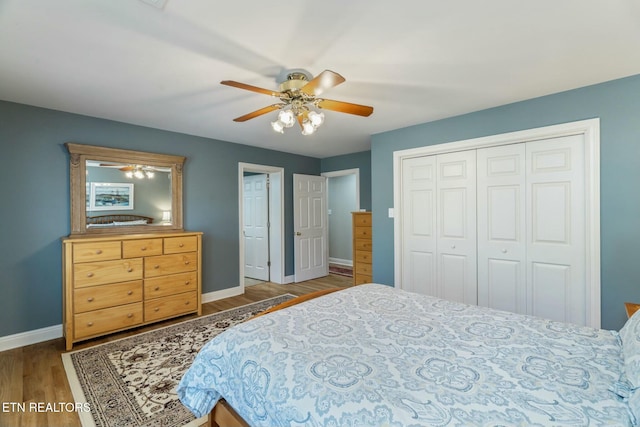 bedroom featuring a closet, baseboards, a ceiling fan, and wood finished floors