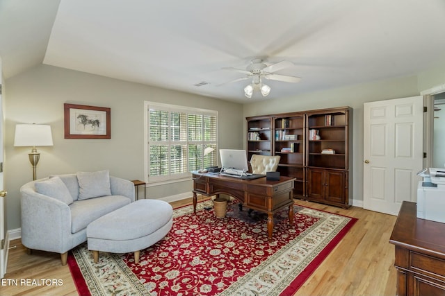 office space with ceiling fan, visible vents, vaulted ceiling, light wood finished floors, and baseboards