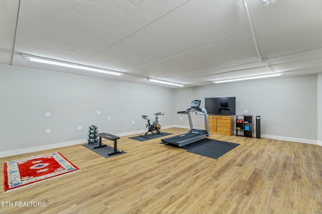 exercise room with baseboards and wood finished floors