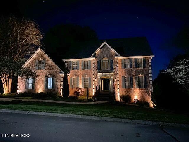 colonial house with a yard and brick siding