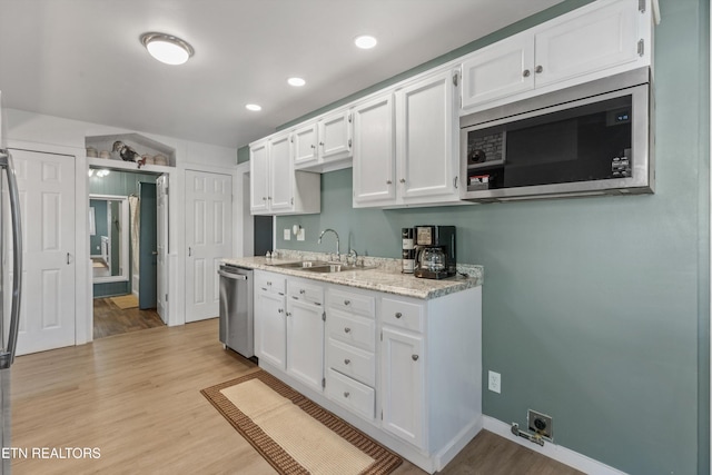 2214 Lincoln St, Knoxville, TN 37920 - kitchen featuring stainless steel appliances, white cabinets, a sink, and light wood-style flooring