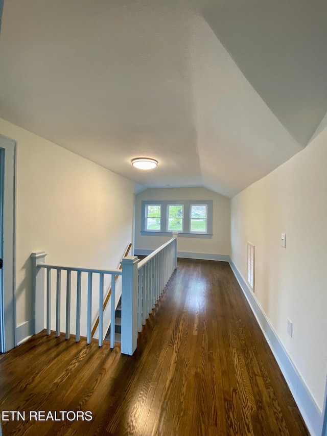 bonus room featuring dark wood-style flooring, baseboards, and vaulted ceiling