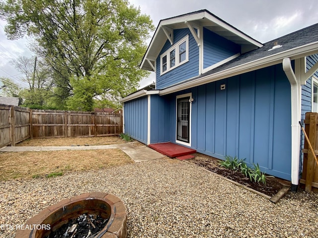 back of house featuring board and batten siding, an outdoor fire pit, and a fenced backyard