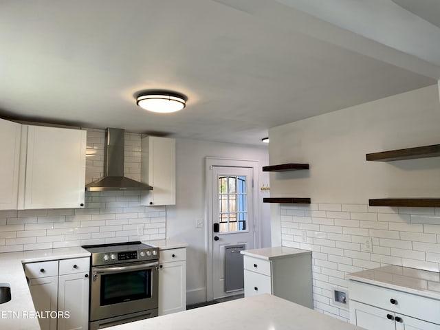 kitchen with stainless steel electric range oven, backsplash, open shelves, and wall chimney exhaust hood